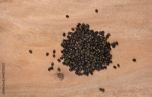 fresh raw papaya seeds from ripe papaya on a wooden table top, beneficial and highly nutritious edible black, shiny, wet seeds, heart healthy food, taken from above closeup with copy space