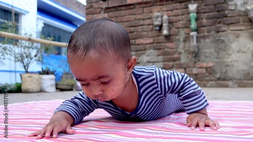 An Infant baby boy is lying on the floor doing mischief. The cutest infant baby is having fun lying on the floor. Portrait of a cute baby boy. Close-up view. photo