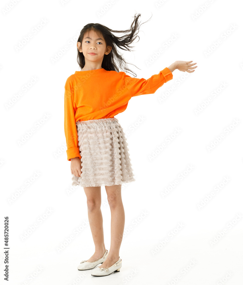 Naklejka premium Full body cutout isolated studio shot of Asian young primary schoolgirl model in casual orange shirt and skirt outfit standing holding hand spreading long hair blowing with wind on white background