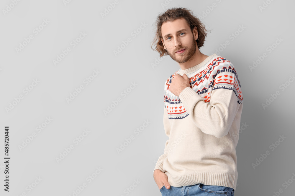Handsome young man in knitted sweater on grey background Handsome young man in knitted sweater on grey background