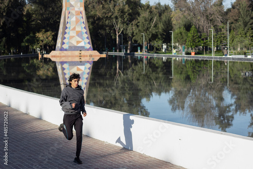 young athlete jogging in the open-air park among nature by the lake in the morning photo