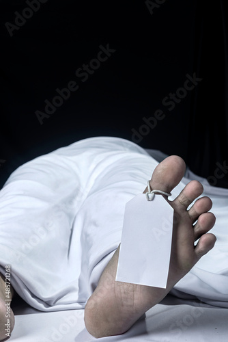Human corpse covered with a sheet and name tag on toe