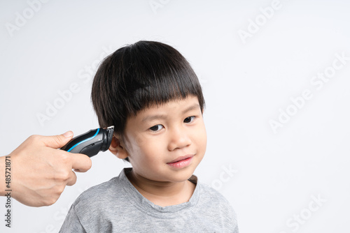 Asian boy got hair cut at home by his mother with electric cordless clippers