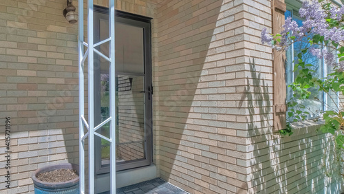 Panorama Exterior of a home with storm door and a bricks siding