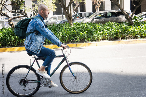 Bald young man dressed casual riding a bike in the city