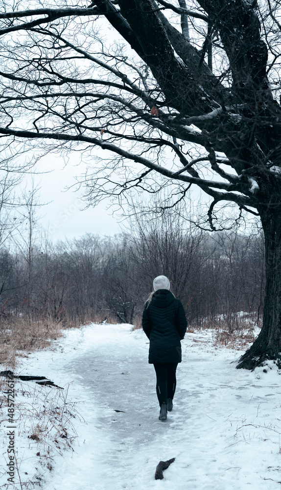 Woman taking a walk through the forest on a cold winters day Woman taking a walk through the forest on a cold winters day