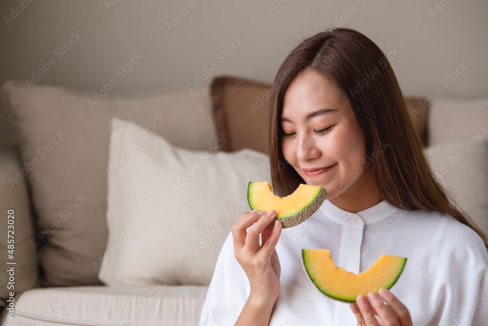 Portrait image of a young woman holding and eating two pieces of Cantaloupe melon Portrait image of a young woman holding and eating two pieces of Cantaloupe melon