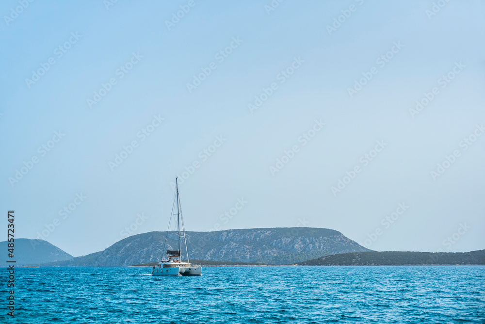Catamaran sailing boat in the Aegean Sea under the clear blue sky on a sailing vacation, Peloponnese, Greece, Europe, background with copy space
