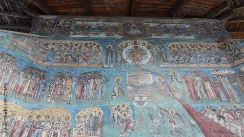 Detail Of Murals In Blue Exterior Walls Of Voronet Monastery In Suceava, Romania. Tilt-down Shot  photo