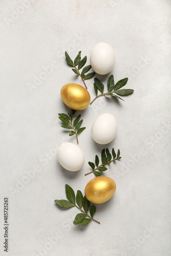 Beautiful Easter eggs and plant leaves on light background