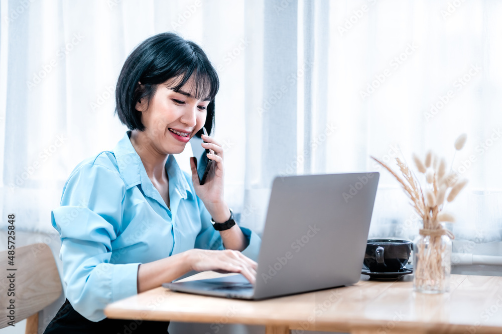 Smiling with dental braces asian freelance people business female hold pick up smartphone casual working with laptop computer with coffee cup and smartphone in coffee shop like the background Smiling with dental braces asian freelance people business female hold pick up smartphone casual working with laptop computer with coffee cup and smartphone in coffee shop like the background