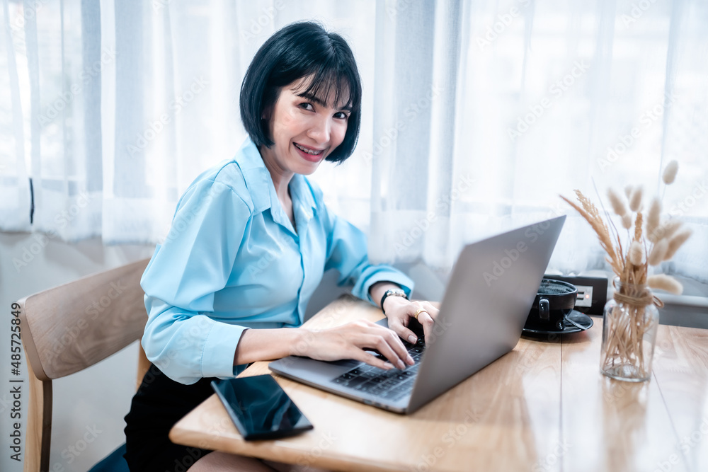 Smiling with dental braces of asian freelance people business female casual working with laptop computer and notebook with coffee cup and smartphone in cafe interior in coffee shop Smiling with dental braces of asian freelance people business female casual working with laptop computer and notebook with coffee cup and smartphone in cafe interior in coffee shop