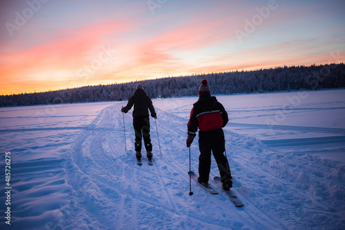 Bild auf Leinwand Skiing on the frozen lake at Torassieppi at sunset, Lapland, Finland