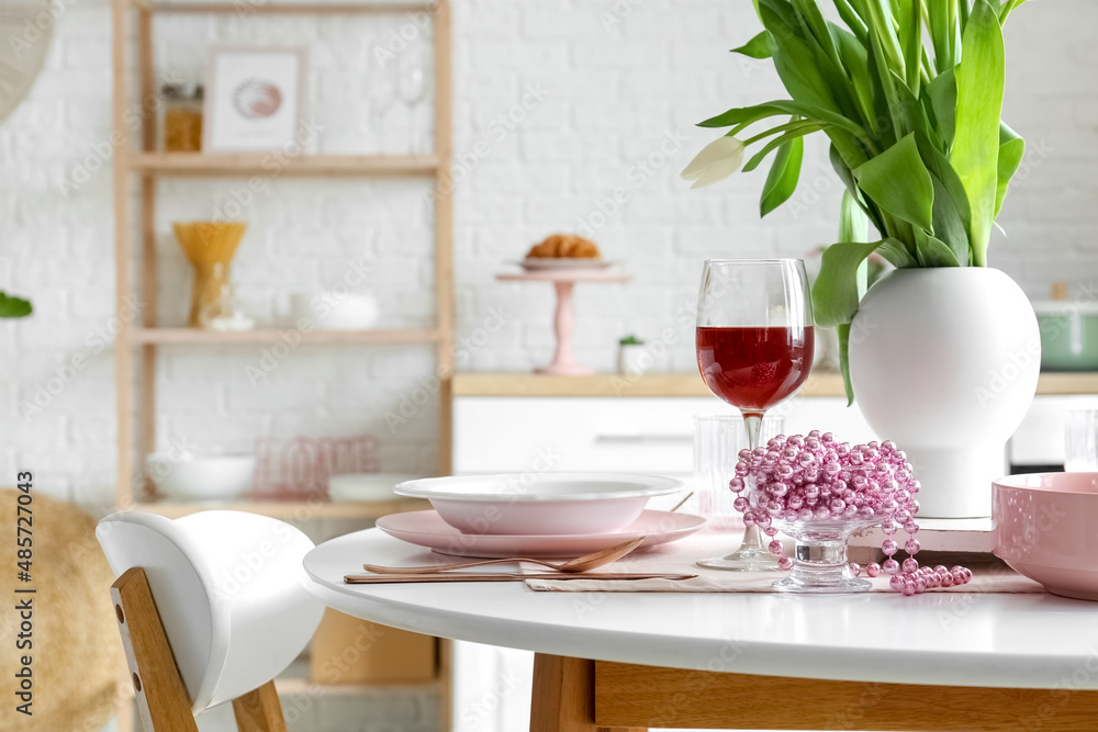 Dining table with setting and glass of wine for International Women's Day celebration in kitchen Dining table with setting and glass of wine for International Women's Day celebration in kitchen
