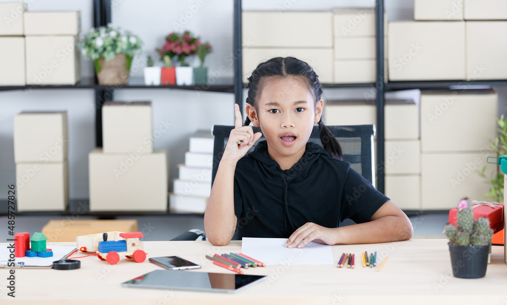 Asian young thoughtful doubtful preschooler girl artist sitting thinking holding color pencil in hand on forehead at workshop desk with tablet toys ready to drawing painting picture on white paper Asian young thoughtful doubtful preschooler girl artist sitting thinking holding color pencil in hand on forehead at workshop desk with tablet toys ready to drawing painting picture on white paper