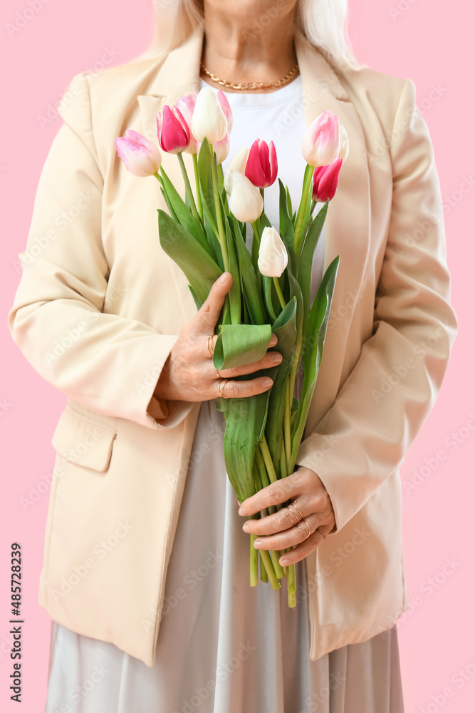Mature woman holding bouquet of tulips on pink background, closeup. International Women's Day celebration Mature woman holding bouquet of tulips on pink background, closeup. International Women's Day celebration