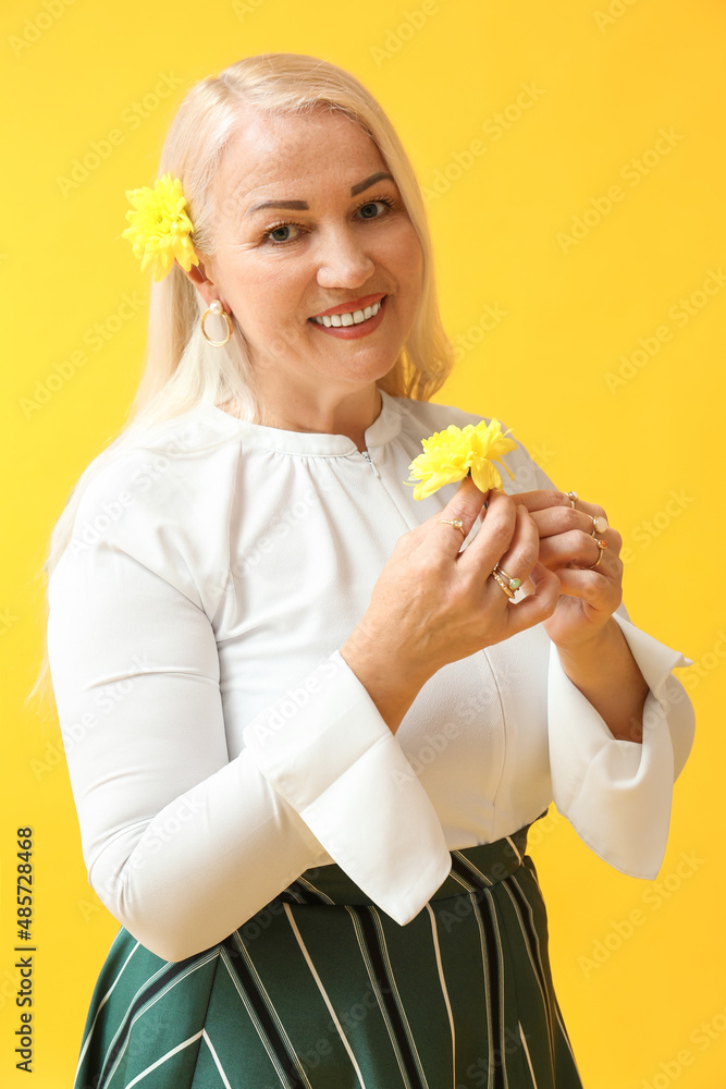 Smiling mature woman with beautiful flowers on yellow background. International Women's Day celebration Smiling mature woman with beautiful flowers on yellow background. International Women's Day celebration