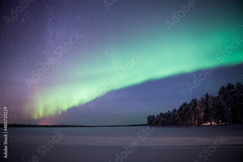 Northern Lights (aurora borealis) over a snow covered icy frozen lake in winter in Finnish Lapland, inside Arctic Circle in Finland © Matthew