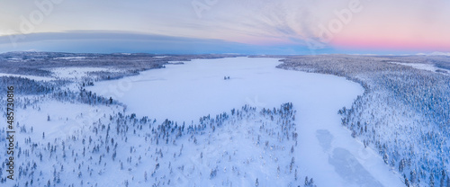 Snow covered lake and forest winter landscape showing amazing Lapland scenery in Scandinavia in Finland drone © Matthew
