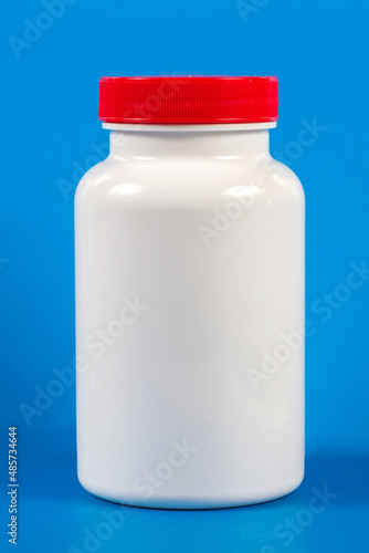 A white plastic jar without a sticker on a blue background. A can with a close-up of the red lid.