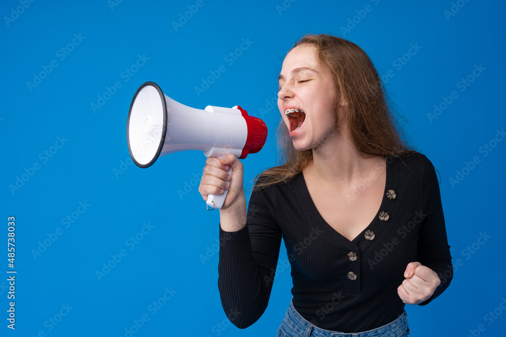 Teen girl making announcement with megaphone at blue studio Teen girl making announcement with megaphone at blue studio