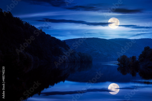 beautiful scenery with lake at night. dark clouds reflecting on the water surface. wonderful autumnal landscape in mountains in full moon light © Pellinni