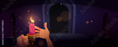 Hand holding candle in dark dungeon or medieval castle at night. Vector cartoon illustration of human hands with candlestick with burning fire in old room with stone walls and arch