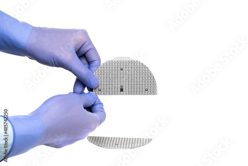 A hands in a rubber glove hold broken multilayer semiconductor silicon wafer with a microcircuit chip of a powerful Darlington transistor isolated on a white background photo