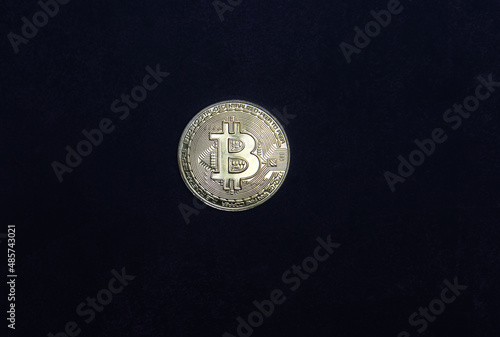 Golden bitcoin isolated on dark background.