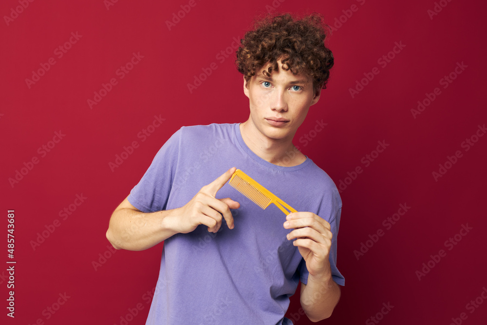 portrait of a young curly man in purple t-shirts with a comb Youth style portrait of a young curly man in purple t-shirts with a comb Youth style