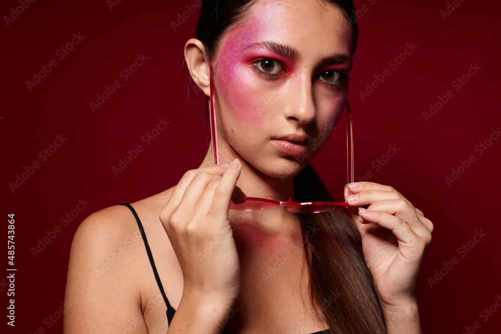 Obraz premium Portrait of beautiful young woman pink glasses bright makeup posing black jersey isolated background unaltered