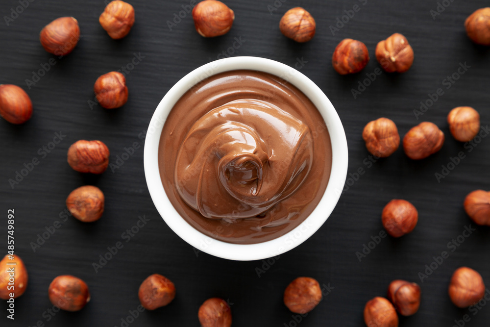 Homemade Chocolate Hazelnut Spread in a Bowl on a black surface, top view. Flat lay, overhead, from above. Space for text. Homemade Chocolate Hazelnut Spread in a Bowl on a black surface, top view. Flat lay, overhead, from above. Space for text.