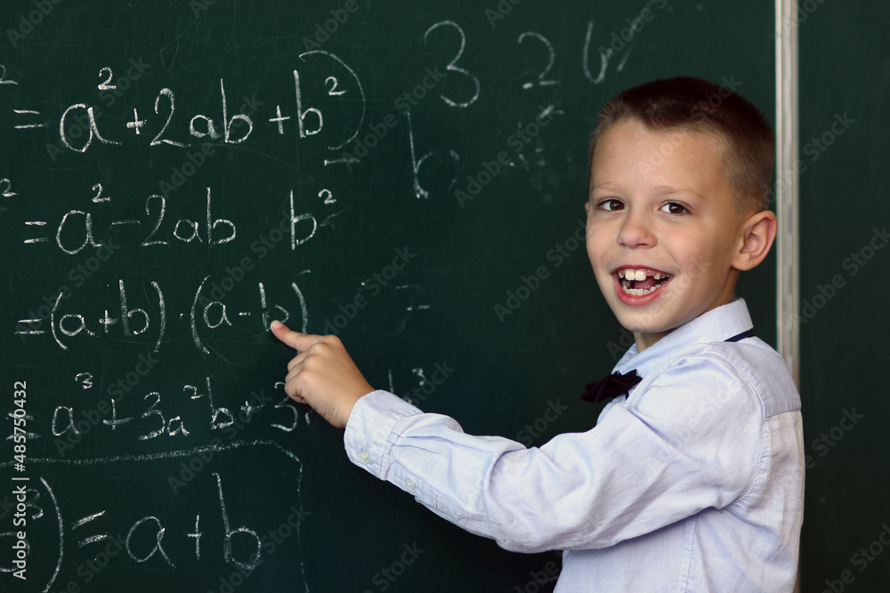 A Happy child child standing at the blackboard in the school class at the lesson A Happy child child standing at the blackboard in the school class at the lesson