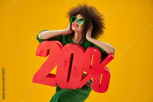 Portrait of a charming lady green dress afro hairstyle dark glasses twenty percent in hands color background unaltered