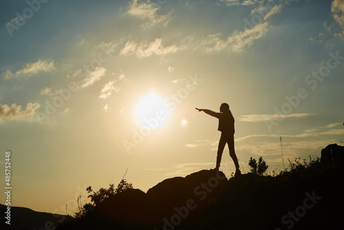Silhouette of a girl during sunset in the mountains. The concept of victory, achievement and perfection.