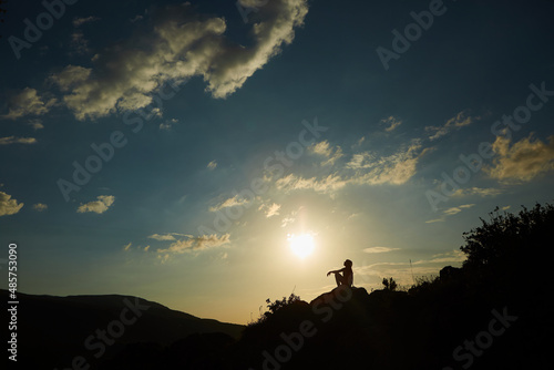 Silhouette of a girl during sunset in the mountains. The concept of victory, achievement and perfection.