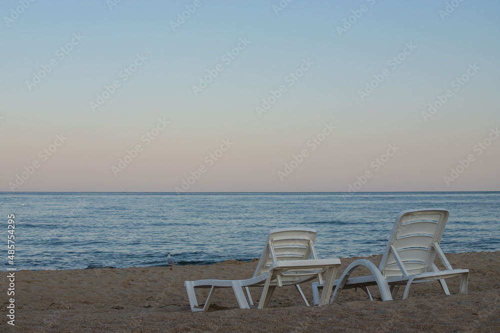 Two sunbeds on a sandy calm beach with turquoise sea water and white sand Two sunbeds on a sandy calm beach with turquoise sea water and white sand