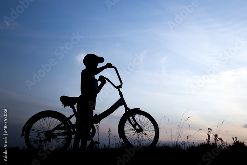 silhouette of a boy on a bicycle in nature © Kostia