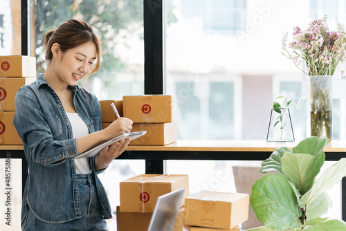 Woman packing item that she sells online. Young start up small business owner packing cardboard box at workplace. Freelance woman seller prepare parcel box of product for deliver to customer.