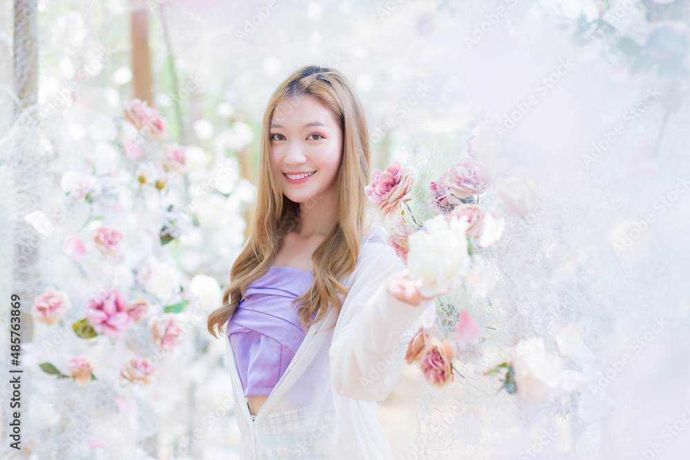 Asian beautiful woman smiles and stands in white rose flower garden as natural , luxury theme