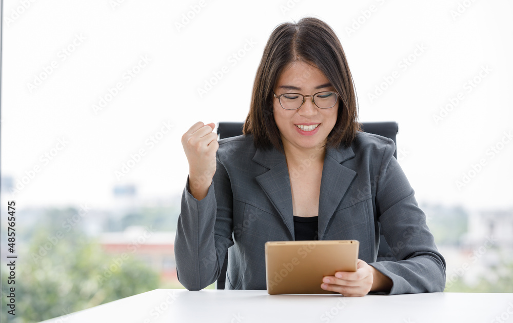 Portrait shot of Asian happy female employee staff sitting smiling while shopping from online store via tablet computer in company office during working. Portrait shot of Asian happy female employee staff sitting smiling while shopping from online store via tablet computer in company office during working.