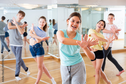 Portrait of emotional teenager girl doing dance workout during group class in studio