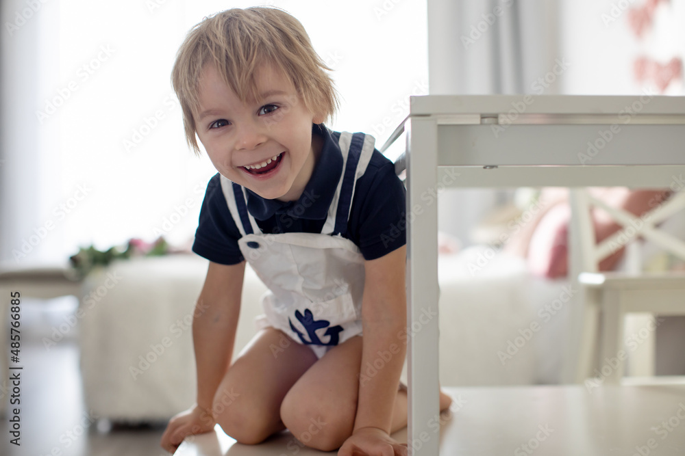 Cute blond toddler child, boy, playing with colorful trains and railroad at home Cute blond toddler child, boy, playing with colorful trains and railroad at home