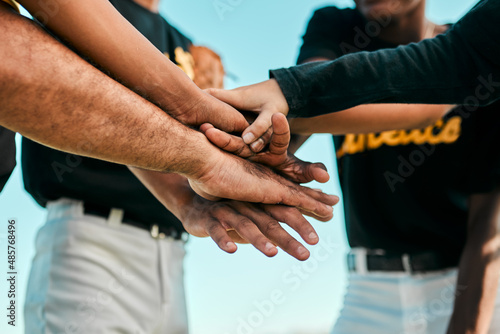They all work together for a single purpose. Shot of a team of young baseball players joining their hands together in a huddle during a game.