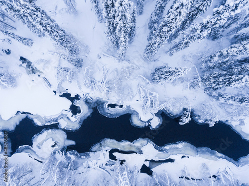 Aerial of frozen river and snow covered forest winter landscape showing amazing Lapland scenery in Scandinavia in Finland drone