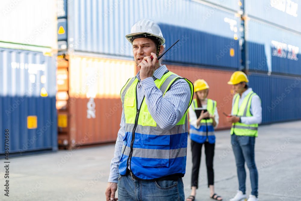 Foreman using radio walkie talkie control loading containers box in cargo for import export, Professional engineer work checking loading containers box. Foreman using radio walkie talkie control loading containers box in cargo for import export, Professional engineer work checking loading containers box.