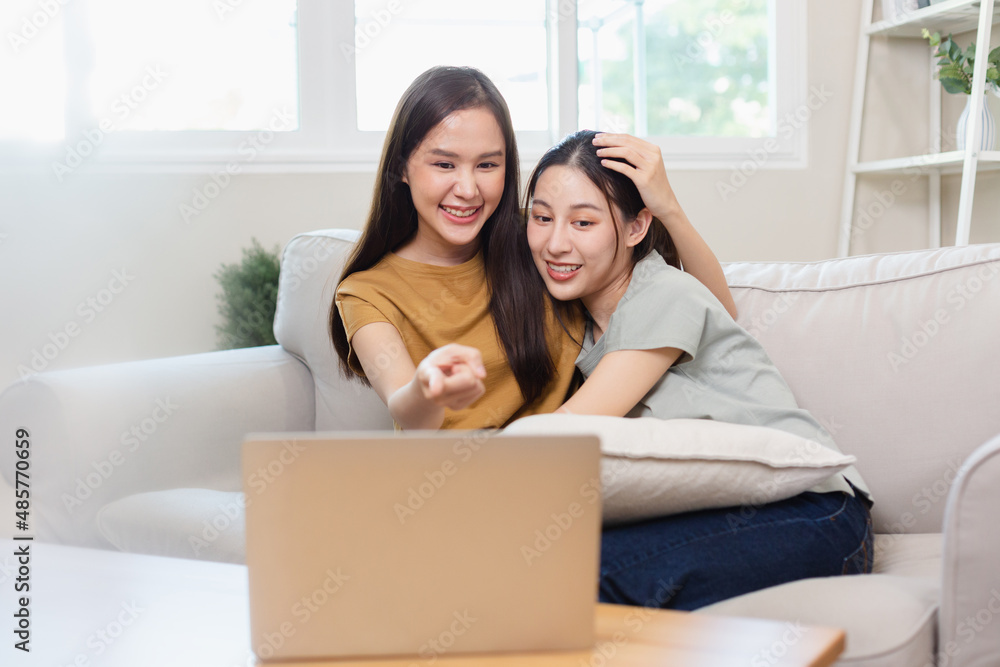 Happy asian women lesbian couple relax time watching movie media online on laptop in living room. homosexual couple hugging each other in love. Happy asian women lesbian couple relax time watching movie media online on laptop in living room. homosexual couple hugging each other in love.