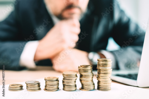 Investment planning concept, businessman looking at coin stack at office desk
