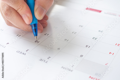 Woman hand with pen writing on calendar date business planning appointment meeting concept