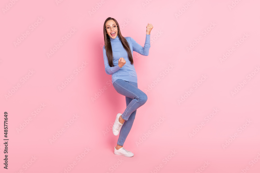 Photo of astonished champion lady rejoice win wear specs blue turtleneck jeans sneakers isolated pink color background